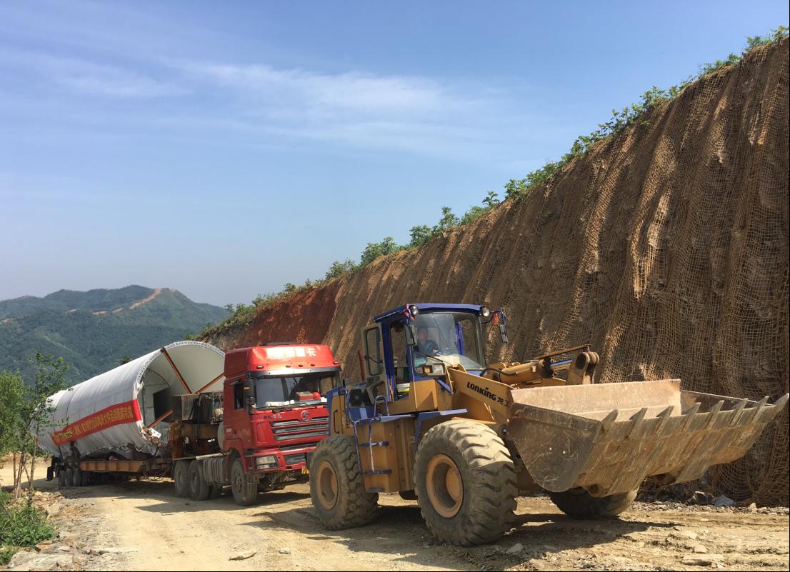 A loader helps to tow the windmill tower to the mountainous district