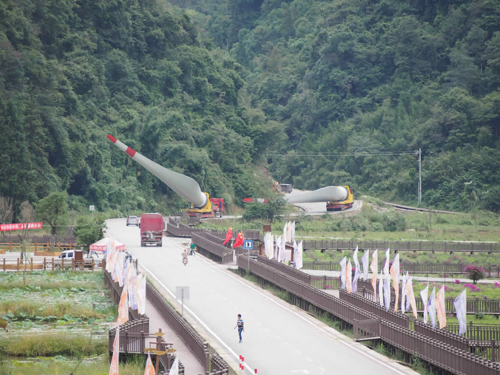 Windmill blade adaptor lowers the wind blade to pass under electric wires on a public road